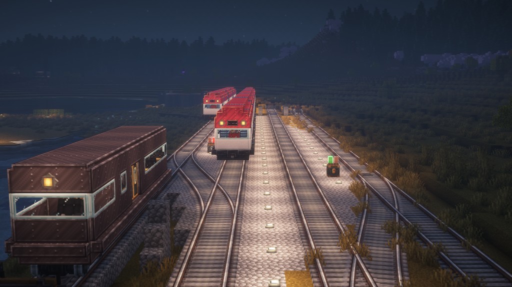 Rail yard at night with multiple trains on parallel tracks.